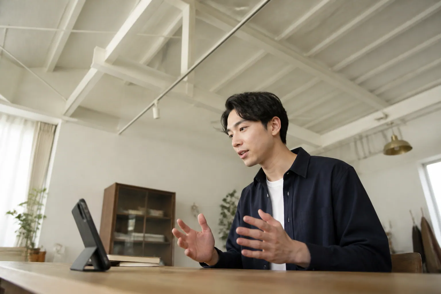 自宅の机に立てかけたスマートフォンに向かって話す候補者