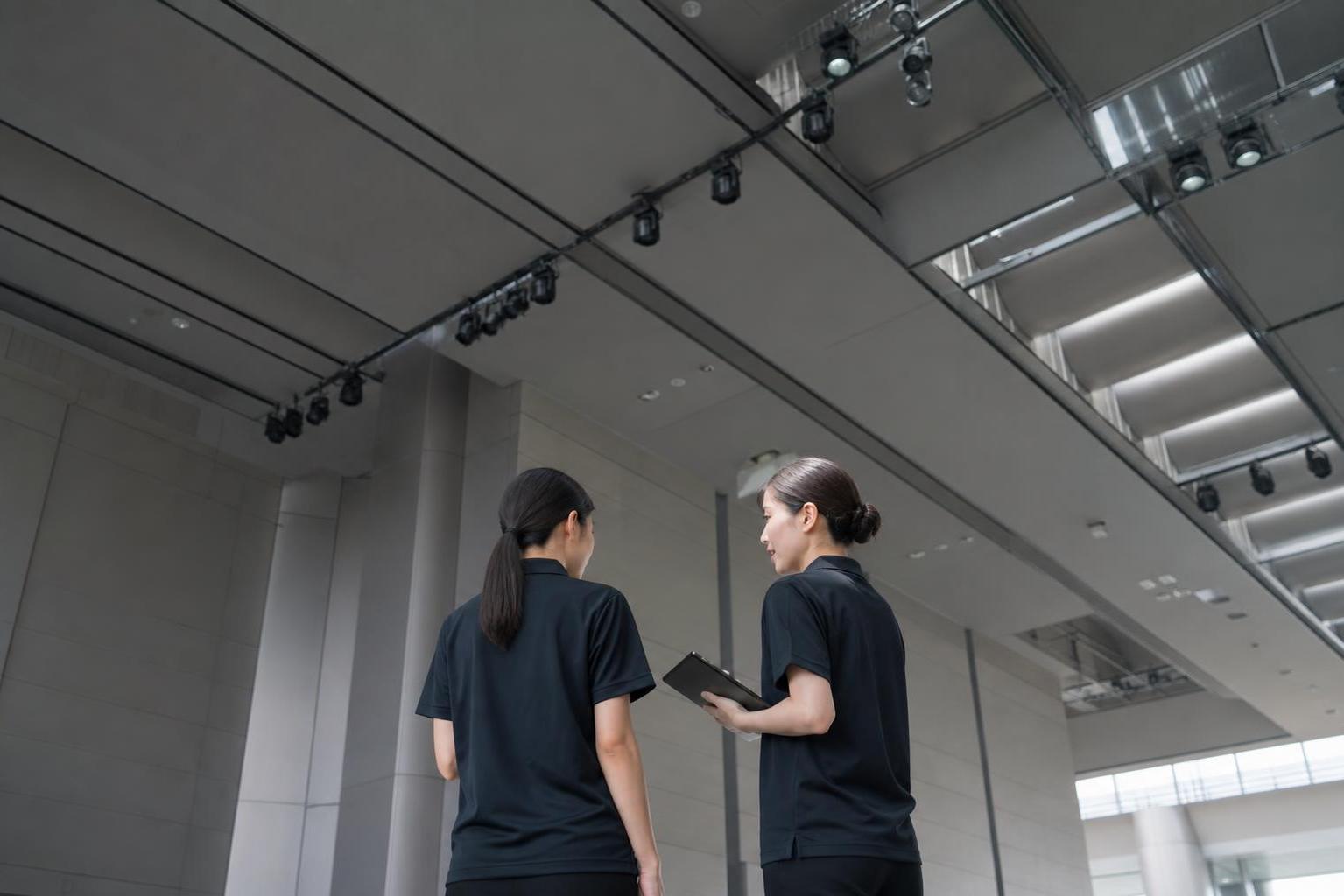 ホールで手順を確認する制服のスタッフ2人