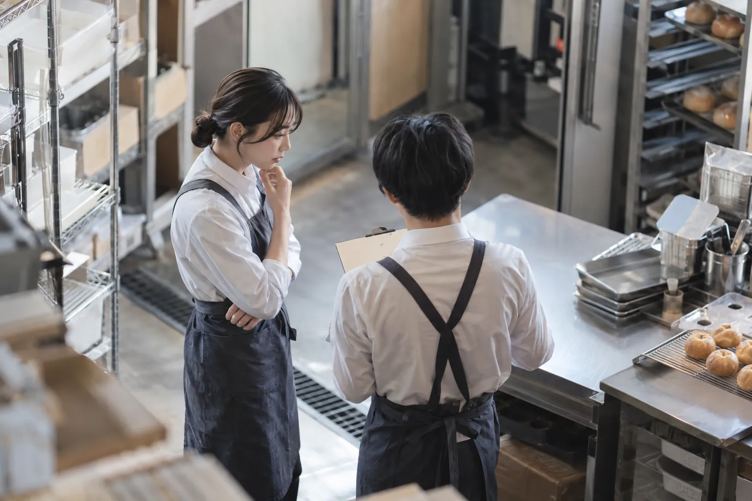 バックヤードで短い打ち合わせをする制服のスタッフ2人