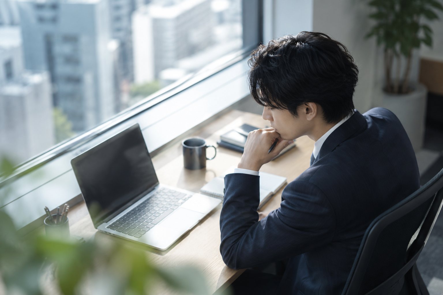 窓際の席で静かに考える社員